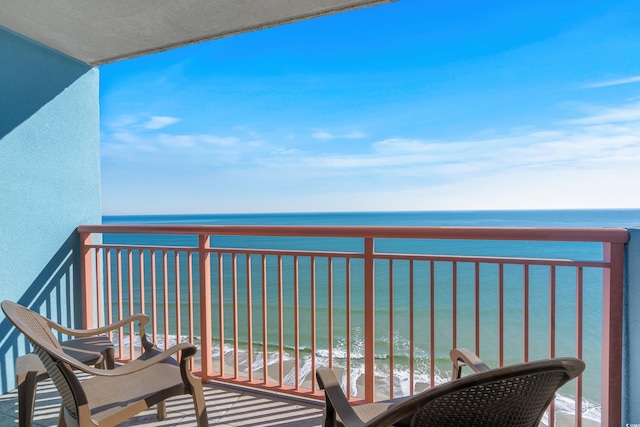 balcony with a water view and a view of the beach