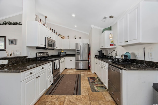 kitchen with hanging light fixtures, appliances with stainless steel finishes, vaulted ceiling, white cabinets, and ornamental molding