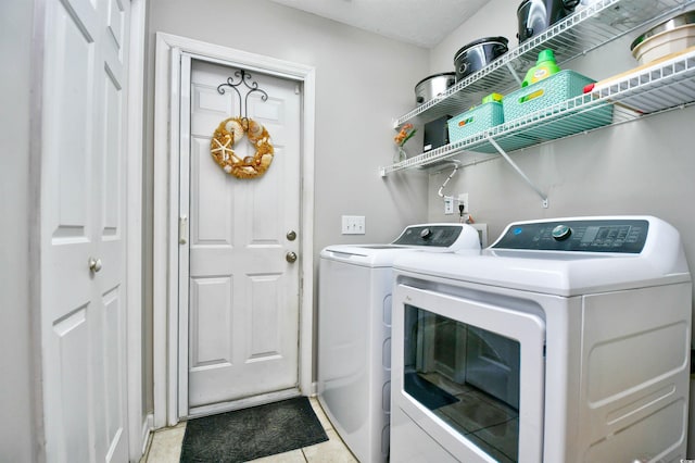 clothes washing area featuring light tile patterned flooring and washer and clothes dryer