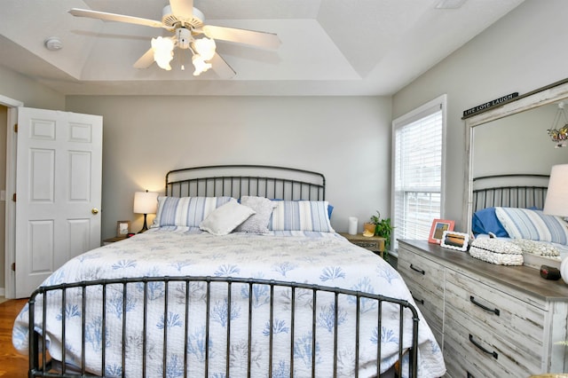 bedroom featuring a raised ceiling, hardwood / wood-style floors, and ceiling fan