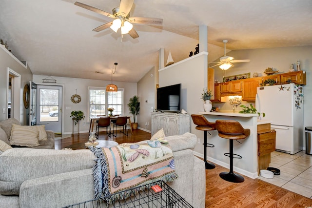 living room featuring lofted ceiling, ceiling fan, and light wood-type flooring