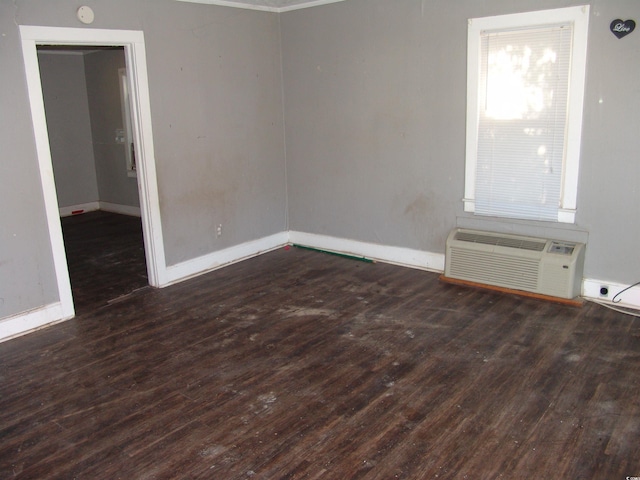 spare room featuring a wall mounted air conditioner and dark wood-type flooring