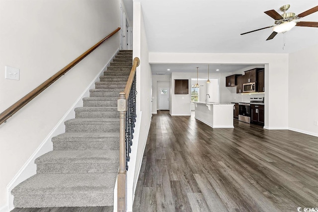 stairway featuring hardwood / wood-style floors, ceiling fan, and sink