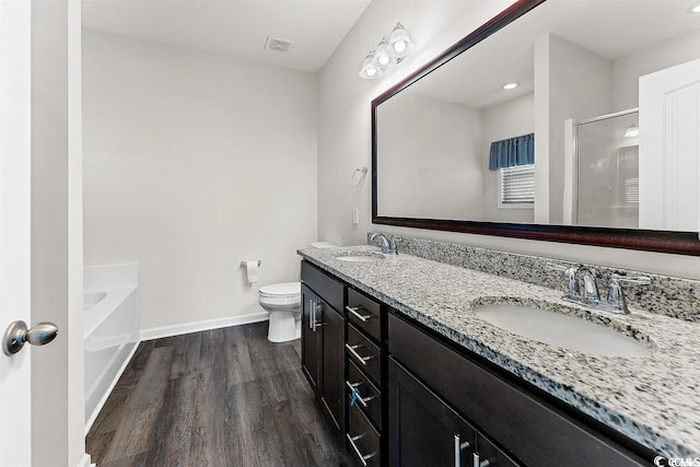 bathroom featuring hardwood / wood-style flooring, vanity, toilet, and a bath