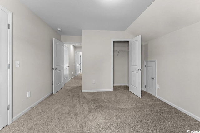 unfurnished bedroom featuring a closet, carpet floors, and vaulted ceiling