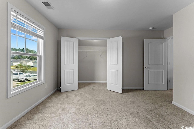 unfurnished bedroom with light carpet and a closet