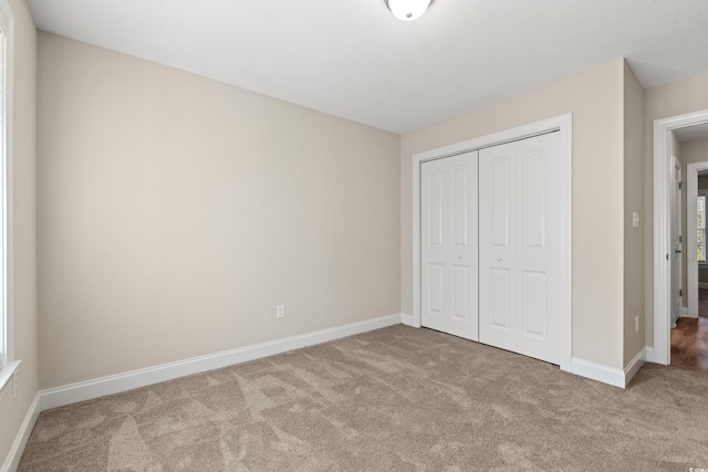 unfurnished bedroom featuring light colored carpet and a closet