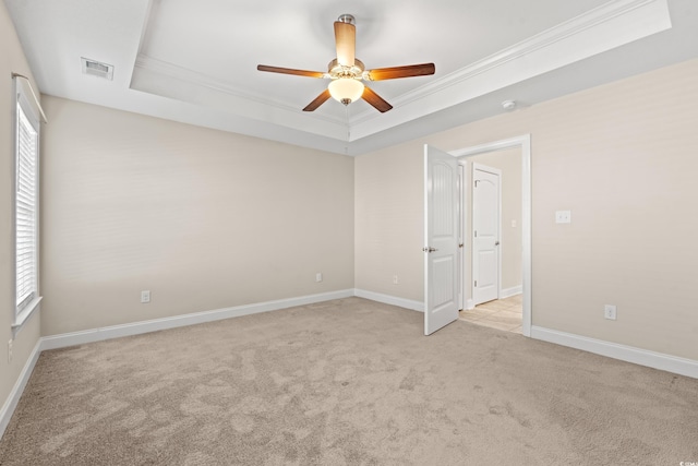 carpeted spare room featuring ceiling fan, a raised ceiling, and crown molding