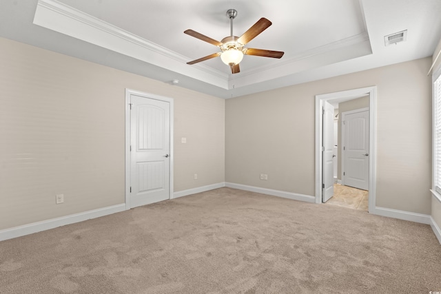 unfurnished bedroom featuring a tray ceiling, ceiling fan, ornamental molding, and light colored carpet