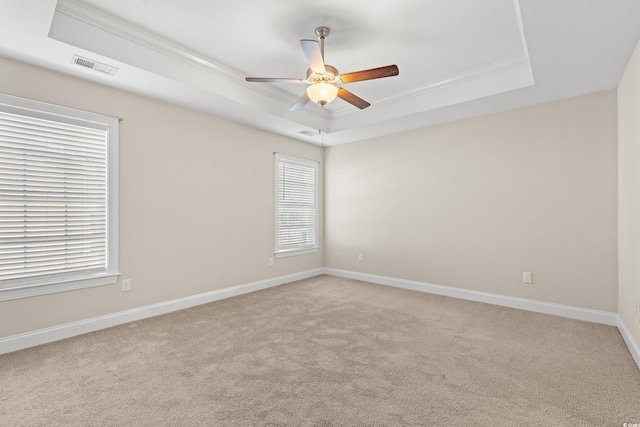 carpeted spare room with a raised ceiling, ceiling fan, and crown molding