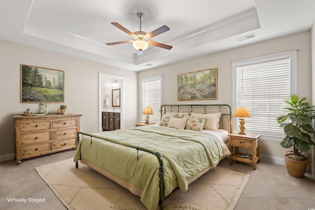 carpeted bedroom featuring ceiling fan, ensuite bathroom, and a tray ceiling