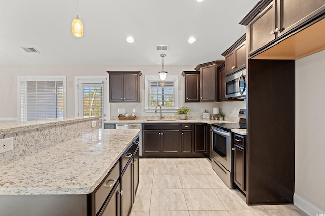 kitchen with dark brown cabinetry, sink, hanging light fixtures, light stone counters, and appliances with stainless steel finishes