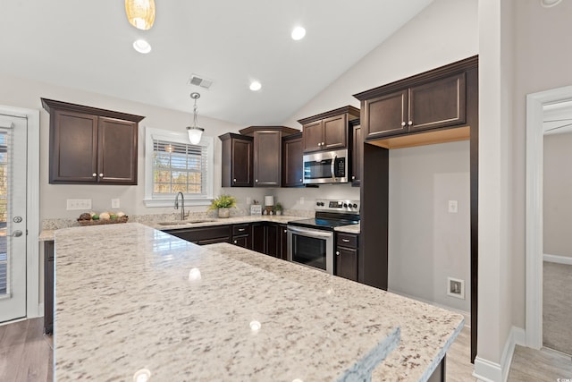 kitchen featuring hanging light fixtures, light stone countertops, sink, and appliances with stainless steel finishes