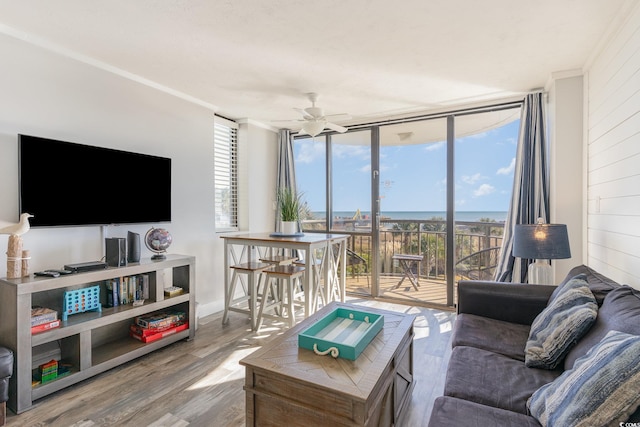 living room featuring a wall of windows, ceiling fan, and hardwood / wood-style flooring