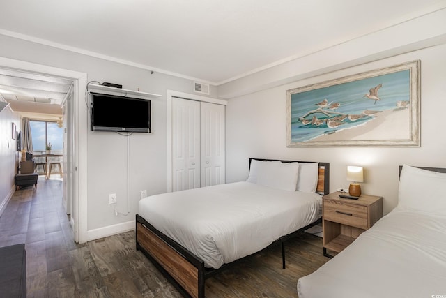 bedroom with dark hardwood / wood-style flooring, crown molding, and a closet