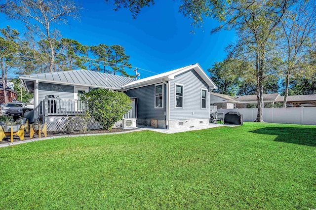 rear view of property featuring a lawn, ac unit, and a deck