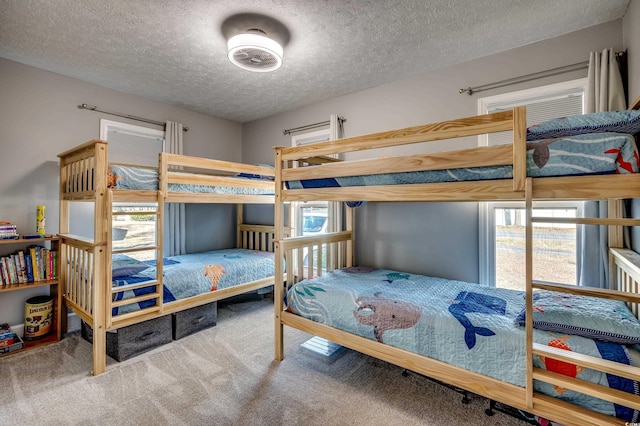 carpeted bedroom featuring a textured ceiling and multiple windows