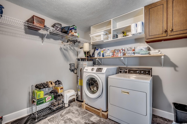 laundry room featuring cabinets, a textured ceiling, washer and clothes dryer, and water heater