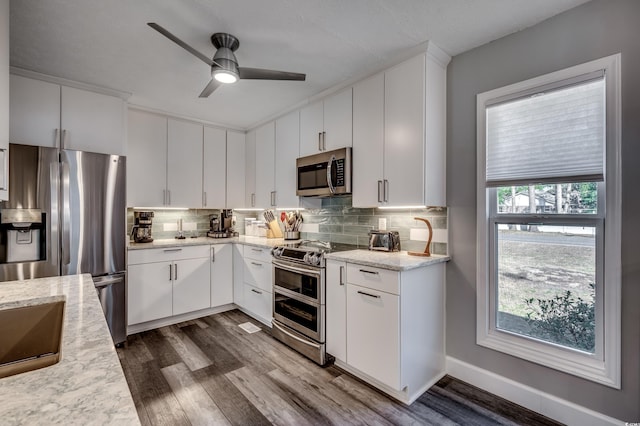 kitchen featuring decorative backsplash, appliances with stainless steel finishes, light stone counters, dark hardwood / wood-style floors, and white cabinetry