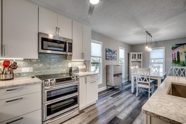 kitchen with stainless steel appliances, pendant lighting, a textured ceiling, decorative backsplash, and white cabinets