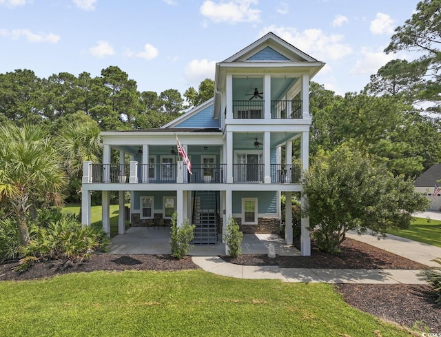 view of front of property with ceiling fan, a patio area, a balcony, and a front lawn