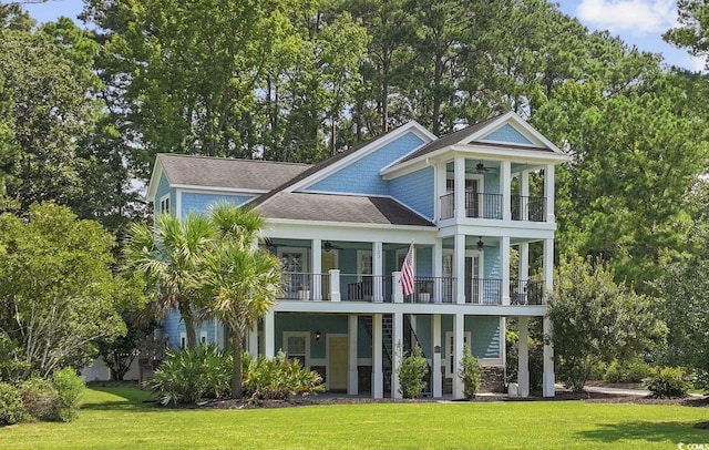 rear view of property with a yard, ceiling fan, and a balcony