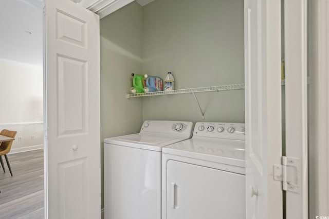 clothes washing area with light hardwood / wood-style floors and washer and dryer