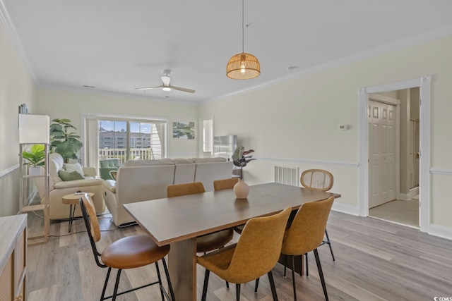 dining room with ceiling fan, ornamental molding, and light hardwood / wood-style floors