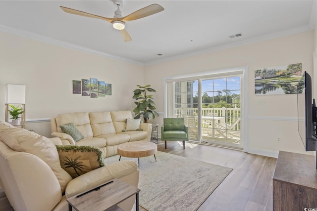 living room featuring ornamental molding, light hardwood / wood-style floors, and ceiling fan