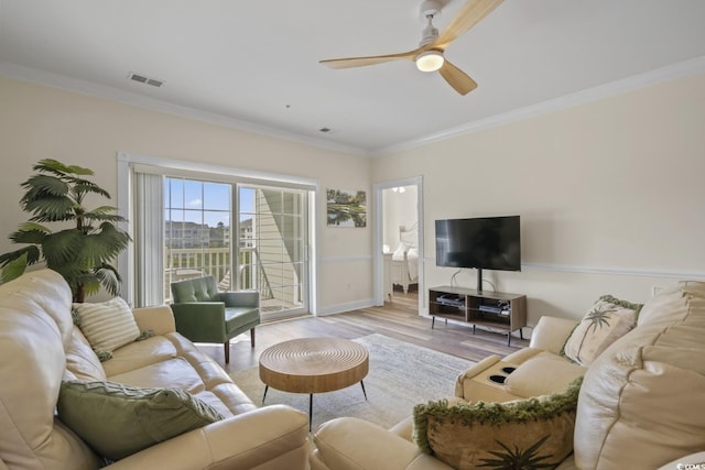 living room with ceiling fan, ornamental molding, and light wood-type flooring