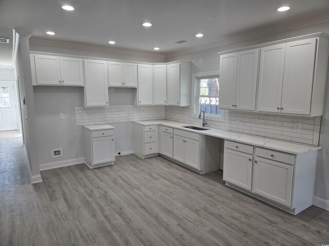 kitchen with white cabinets, sink, crown molding, and hardwood / wood-style floors