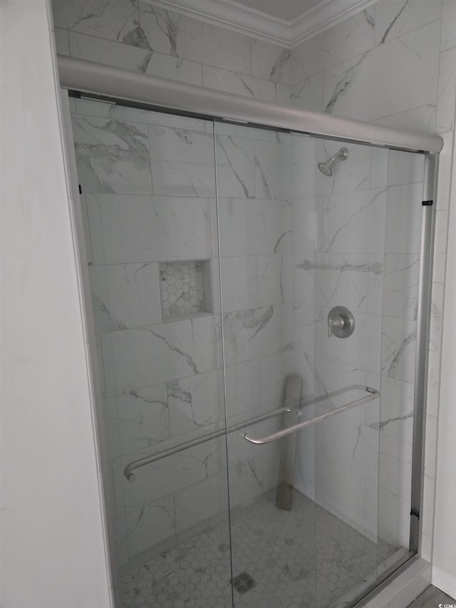 bathroom with a shower with shower door and ornamental molding