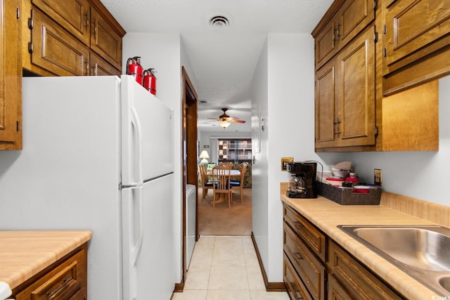 kitchen featuring ceiling fan, sink, white fridge, and light tile patterned floors