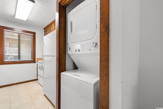 clothes washing area with a textured ceiling, light tile patterned flooring, and stacked washer / drying machine