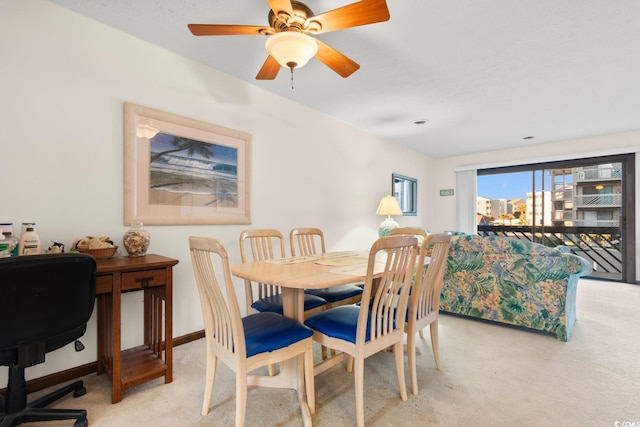 dining space with ceiling fan and light colored carpet