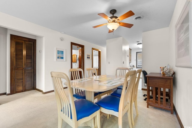 carpeted dining room with ceiling fan