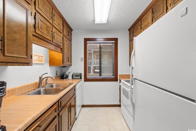 kitchen with a textured ceiling, white appliances, sink, and light tile patterned floors