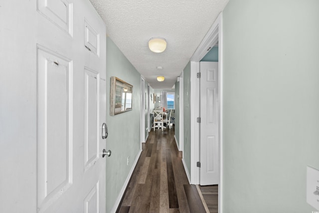 corridor with dark hardwood / wood-style floors and a textured ceiling