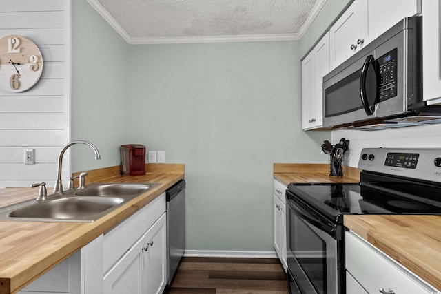 kitchen with wooden counters, stainless steel appliances, white cabinetry, and sink