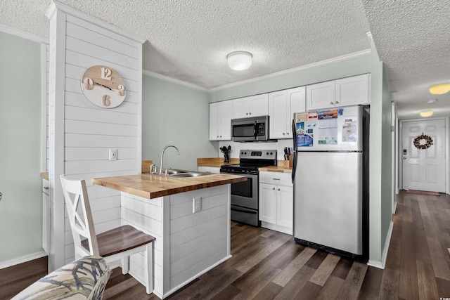 kitchen featuring appliances with stainless steel finishes, crown molding, sink, white cabinets, and butcher block counters