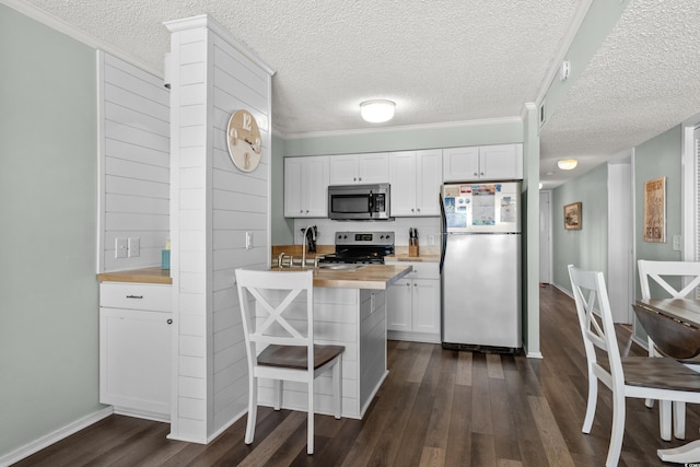 kitchen featuring wooden counters, white cabinets, a kitchen breakfast bar, crown molding, and appliances with stainless steel finishes