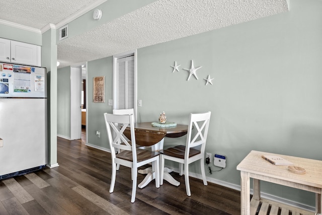 dining room featuring dark hardwood / wood-style flooring, a textured ceiling, and ornamental molding