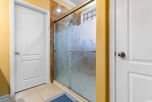 bathroom featuring tile patterned flooring, a shower with shower door, and crown molding