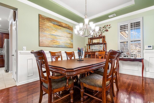 dining space featuring a chandelier, wood-type flooring, and crown molding