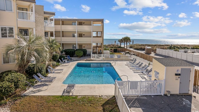 view of pool featuring a water view and a patio