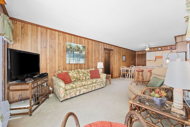 carpeted living room with ceiling fan and wood walls