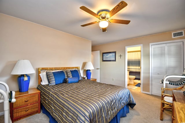 bedroom featuring a closet, ensuite bathroom, ceiling fan, and light colored carpet