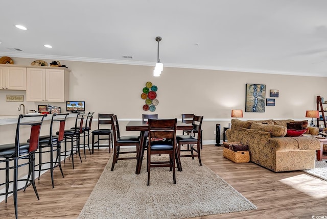 dining space featuring crown molding and light wood-type flooring