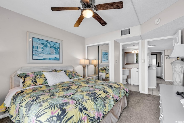 carpeted bedroom featuring ceiling fan, a textured ceiling, and connected bathroom