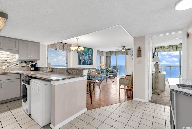 kitchen featuring gray cabinetry, decorative light fixtures, light tile patterned flooring, and backsplash